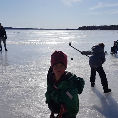 Lapset pelaavat jääkiekkoa järven jäällä