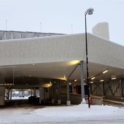 Uutukaisen asemaparkin sisäänajoluiska Joensuussa. Rakennuksen ensimmäisen kerroksen kautta kulkee myös saattoliikenne junille ja busseille.
