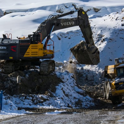 Kaivuri lastaa malmia dumperin kyytiin talvisella kaivoksella.