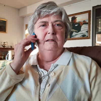 Äldre kvinna som håller en mobiltelefon mot öra.
