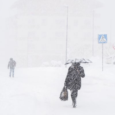 Människor går på en gata medan det snöar.