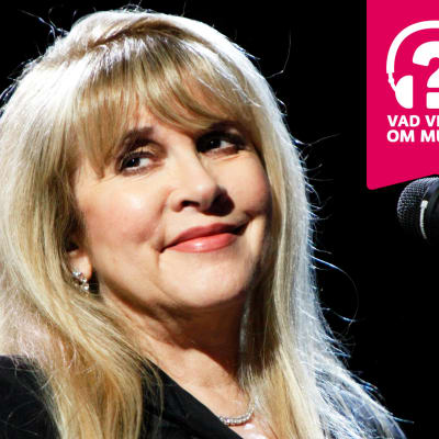 Stevie Nicks ler vid en mikrofon.