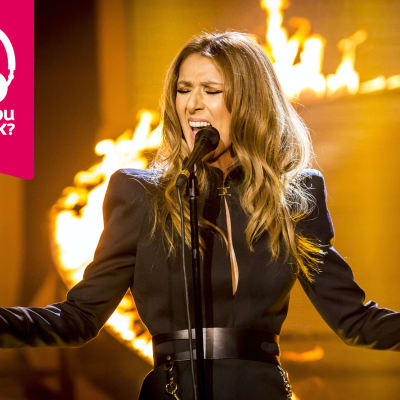 Celine Dion sjunger med armarna utsträckta åt sidorna.