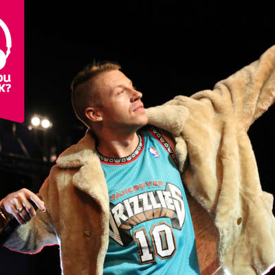 Rapparen Macklemore sträcker upp ena armen med en mikrofon i andra handen.