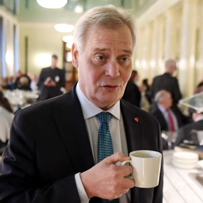 Statsminister Antti Rinne (SDP) med en kaffekopp i handen. Han står i kaféet i riksdagshuset.