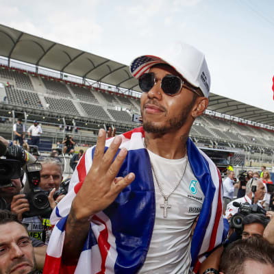 Lewis Hamilton omringad av kameramän.