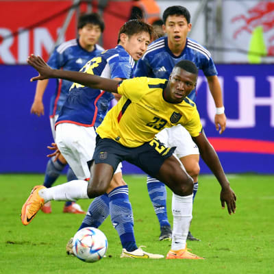 Fotbollsspelare i gult har boll med flera spelare i blått bakom sig.