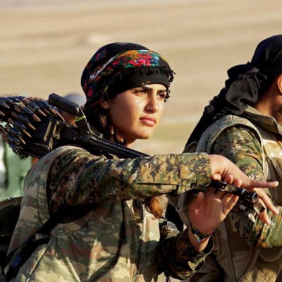 En kvinnlig och en manlig soldat på marsch iklädda kamouflagedräkter. Kvinnan bär ett tungt maskingevär över axeln.