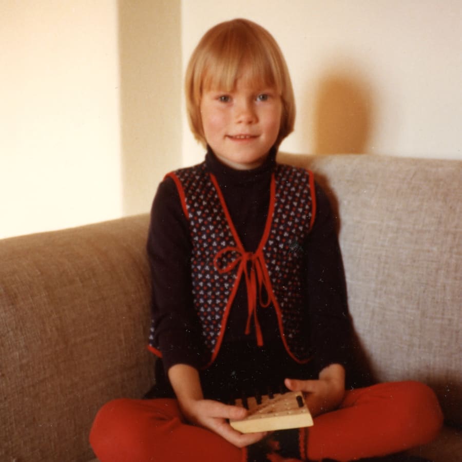 Toimittaja, kirjailija Meri Eskola vuonna 1981 äidin luona. Istuu sohvalla jalat ristissä ja kirja kädessään.