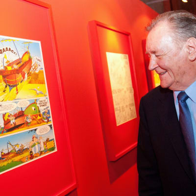 Asterix -sarjakuvan piirtäjä ja käsikirjoittaja Albert Uderzo katselee sarjakuvasivua, joka on seinällä