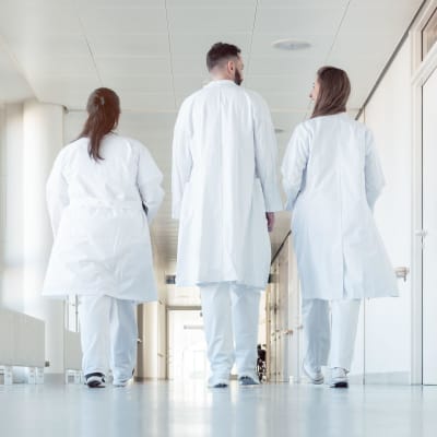 Kolme lääkäriä kävelee käytävällä.