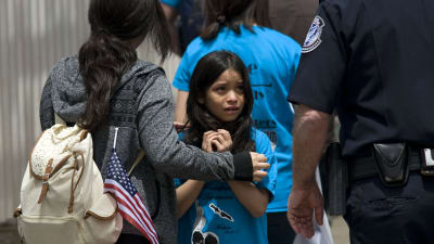 En flicka tittar skrämd upp mot en gränspolis.