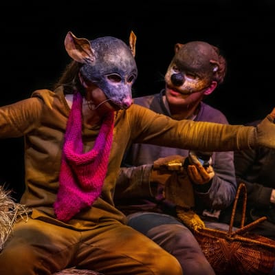 Tre skådespelare i djurmasker sitter på en höbal.
