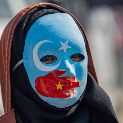 En maskförsedd demonstrant visar sitt stöd för uigurerna under en protestaktion utanför Kinas konsulat i Istanbul