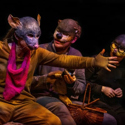 Tre skådespelare i djurmasker sitter på en höbal.