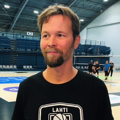 Lahtelainen korisvalmentaja Pieti Poikola kentän laidalla katsoo kamerasta ohi sivulleen