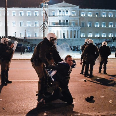 Grekisk kravallpolis grep demonstranter utanför parlamentet i Aten natten till fredagen. 