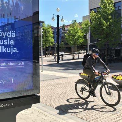 Mies polkupyöräilee Lahden keskustassa 2020. 