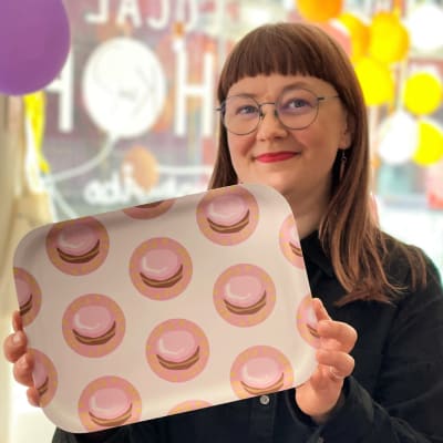 Suunnittelija Henna Jaakkola hymyilee kädessään Piispis-tarjotin. Kuvattu Kui Designin liikkeessä Turussa.