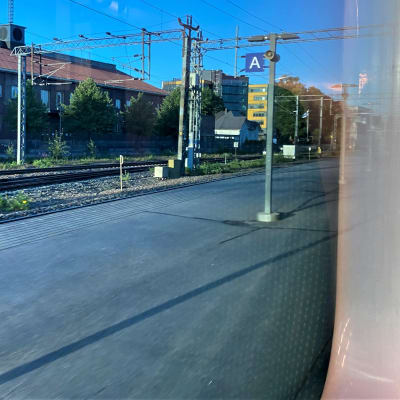 Lahden rautatieasema kuvattuna junasta. Edessä junan ikkunankarmi, tyhjä asemalaituri. 