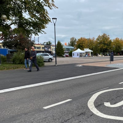 harmaa katu, aukio jossa myyntikoju, autokatu, jalankulkijoita