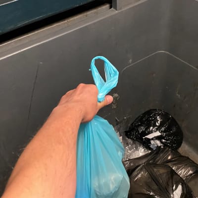 käsi, sininen jätepussi kädessä, muovinen jäteastia