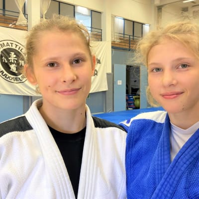 Rovaniemeläiset judokat Louna-Lumia ja Pihla-Mari Seikkula katsovat kameraan judoleirillä Kärkölässä. Toisella on valkoinen ja toisella sininen judopuku.