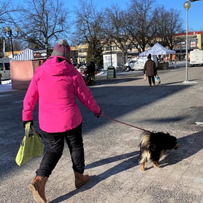 Nainen ulkoiluttaa koiraa Heinolan torin lähellä