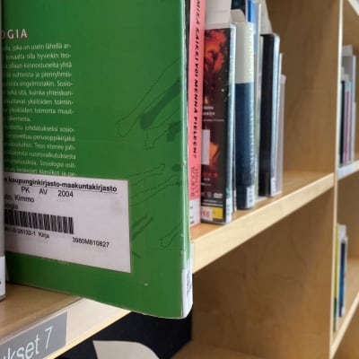 Lähikuvassa on Lahden kirjaston kirjahylly. Yksi kirjoista hyllystä erillään rivistä.