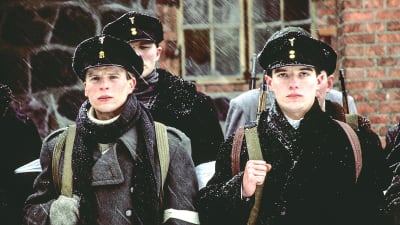 Närbild på unga soldater som står uppställda på rad utomhus i snöfall.