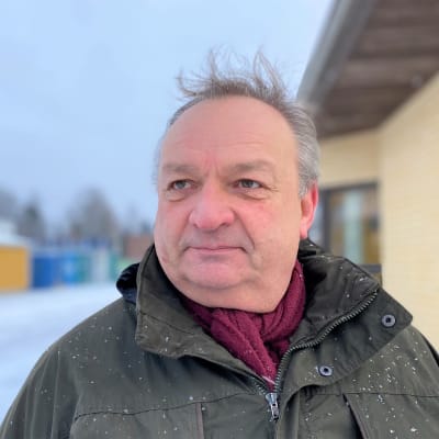 Kärkölän pormestari Markku Koskinen katsoo kaukaisuuteen. On ulkona lumisateessa terveysaseman pihalla. 