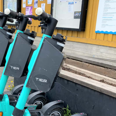 Vihreitä sähköpotkulautoja rivissä. TIer-teksti lukee laudoissa, nojaavat rakennuksen rappusiin Lahdessa. 