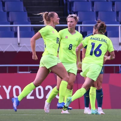 Fridolina Rolfö jublar efter att ha gjort mål, omgiven av två andra svenska spelare.