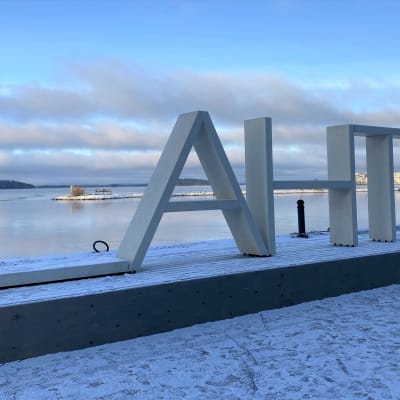Lahti-puuteos Vesijärven rannassa. Lunta maassa ja maisema järvelle taustalla. 