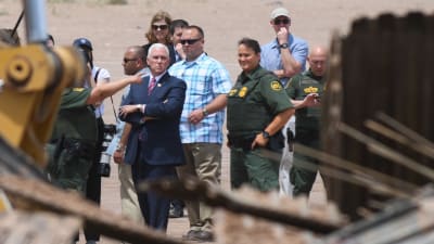 Vicepresident Mike Pence står med armarna i kors och tittar på hur man bygger staket längs gränsen mot Mexico.