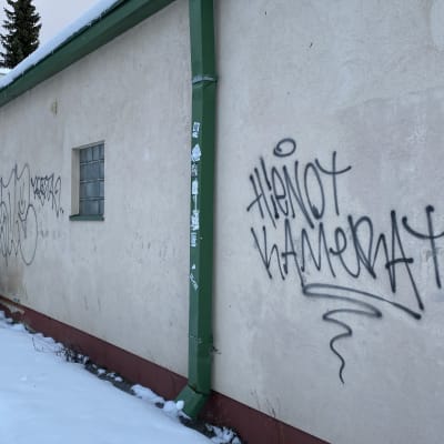 Sprayad text på en vägg. Texten på finska lyder hienot kamerat, vilket kan översättas till fina kameror.