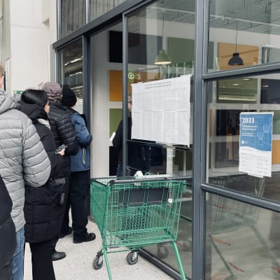 Ihmisiä talvivaatteet päällä jonottamassa enakkoäänestykseen kauppakeskuksessa. 