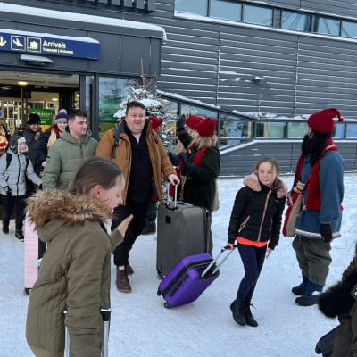 Matkailijoita saapumassa Rovaniemelle lentoaseman ovesta.
