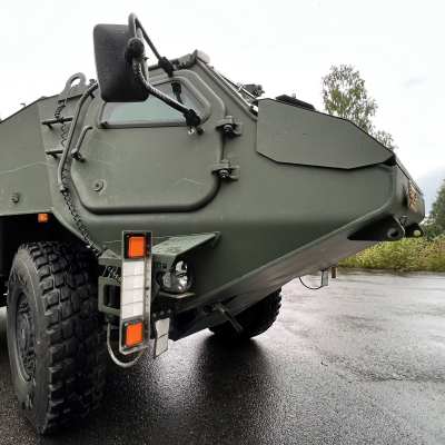 Kuusipyöräinen 6x6 harmaanvihreä panssariajoneuvo seisoo asfaltilla Hämeenlinnassa Patrian piha-alueella.