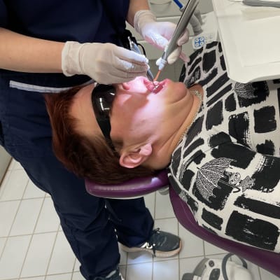 Päivi Asikainen on hammaslääkärituolissa ja hammaslääkäri pitää instrumentteja hänen suussaan.
