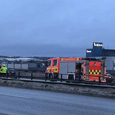 Paloauto ja pelastustyöntekijöitä keltaisissa liiveissä Tampereen läntisellä kehätiellä. Sinisen henkilöauton etupelti on vaurioitunut.