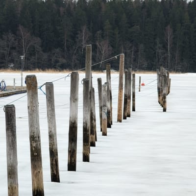 Puotilan venesataman jäätynyttä edustaa ja veneen kiinnitystolppia.