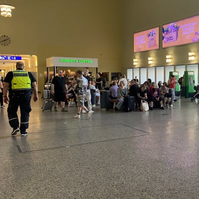 Ihmisiä istuu ja seisoskelee pienissä porukoissa Tampereen rautatieasemalla.