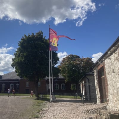 Keli on aurinkoinen mutta liput liehuvat Lappeenrannan Linnoituksessa.