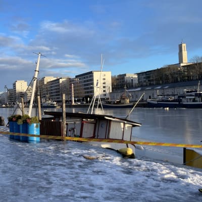 Ett fartyg har sjunkit vid Aura ås strand i centrum av Åbo en solig vinterdag.