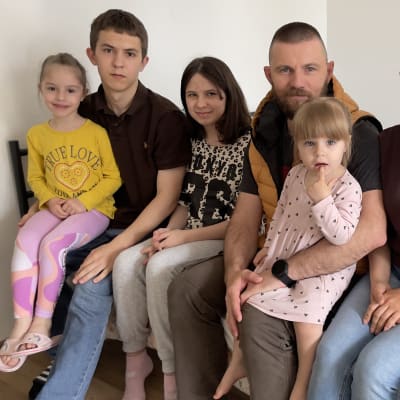 Ukrainasta paennut seitsemän henkinen perhe istuu sängynlaidalla.