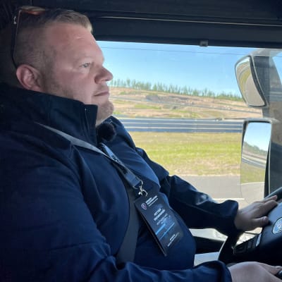 Valion kehityspäällikkö Petteri Tahvanainen ajaa sähkökuorma-autoa Kymiringin moottoriradalla, kädet ohjauspyörässä, katse radassa.