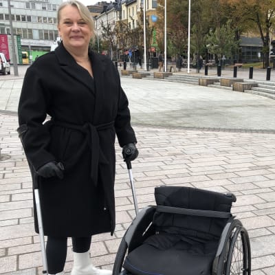 Vammaisvertainen Sanna Koivusalmi seisoo Turun kauppatorilla pyörätuolinsa vieressä.