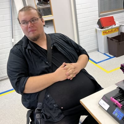 Antti Nenonen istuu 3D-tulostimen vieressä.