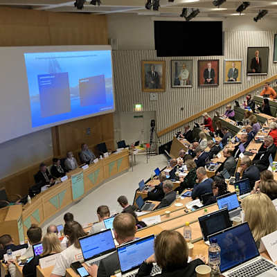 Iso luentosali, jossa aluevaltuston jäsenet osallistuvat kokoukseen.